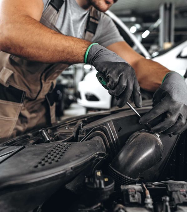 Close up photo of mechanic's hands repairing car engine in car service
