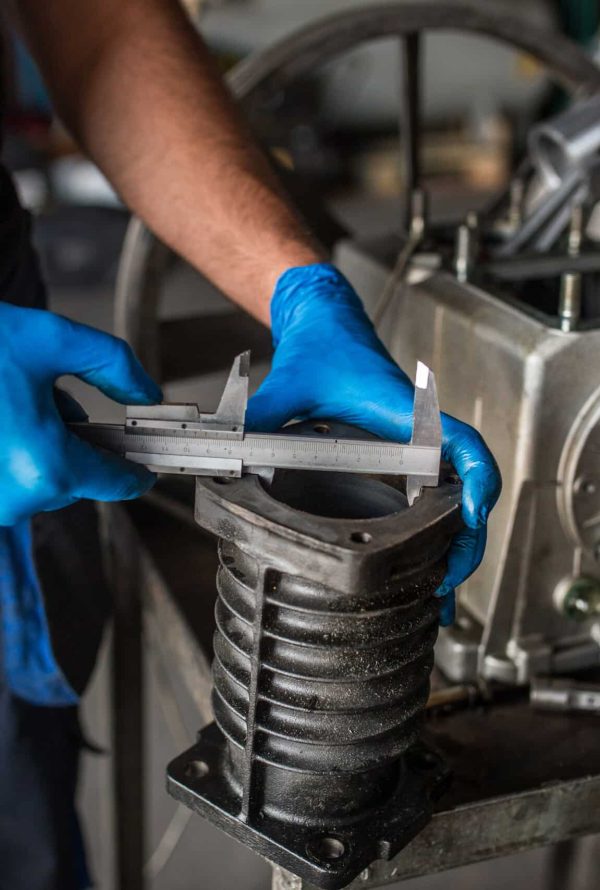 Close-up of a mechanic  using a vernier caliper to measure a cylinder from a compressor engine